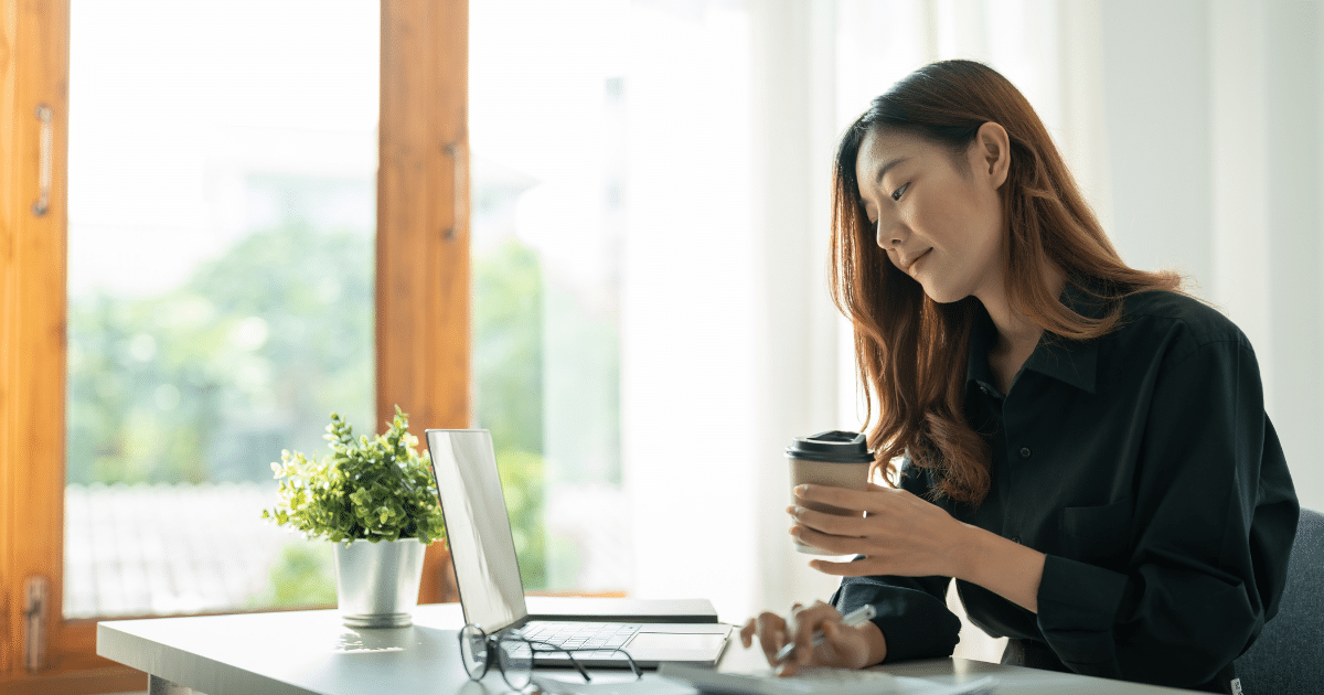 Woman working on a laptop with a coffee cup, exploring flexible business loan options for bad credit.