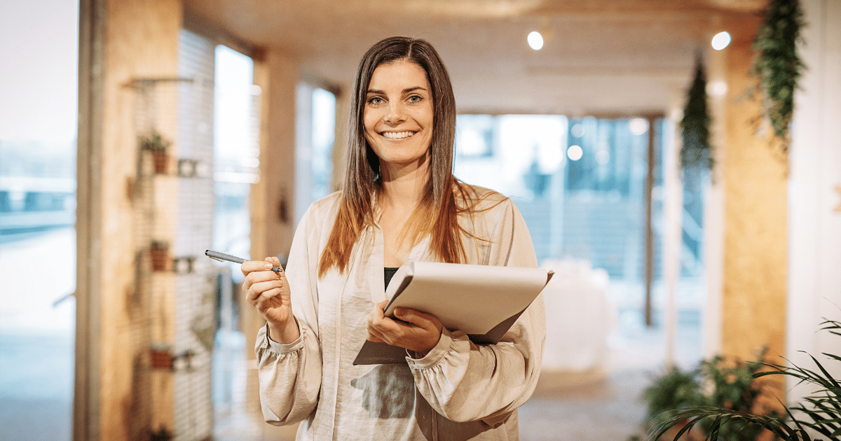 Smiling woman holding a notepad and pen, representing franchise growth and unsecured loans for bad credit.