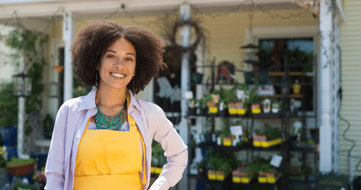 Smiling business owner in an apron outside a plant shop, representing bad credit loans for small business growth.