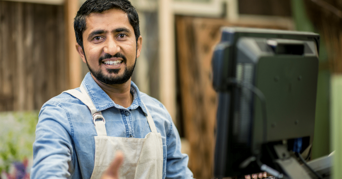 Smiling small business owner at a computer, representing small business financing and growth opportunities.