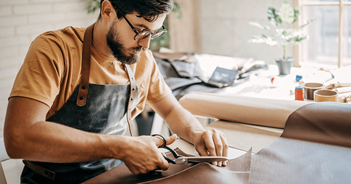 Business owner cutting leather in workshop, showcasing entrepreneurship and craftsmanship for effective financing strategies.