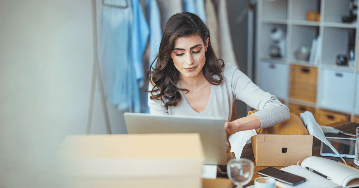 Woman working on a laptop in a cozy office, surrounded by boxes and office supplies, representing tailored medical financing solutions.