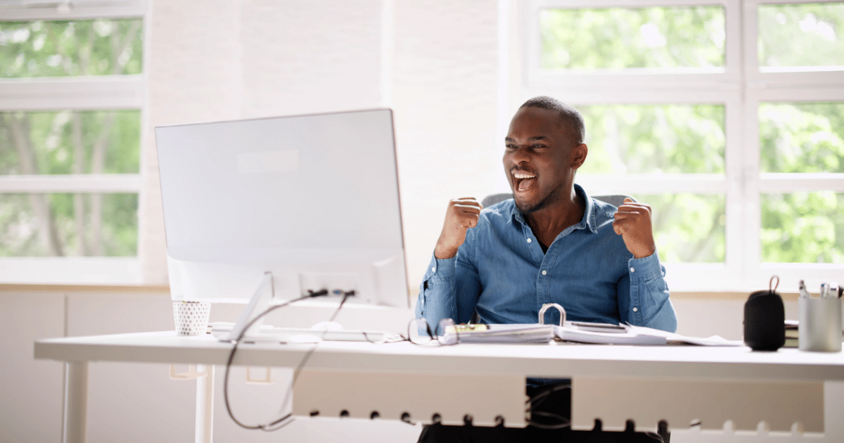 Man celebrating success at a desk, representing family business achievements and effective management strategies.