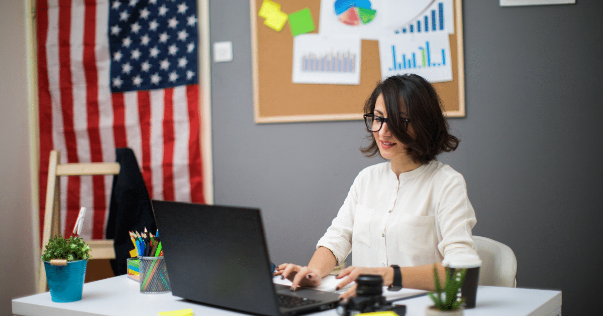 Businesswoman working on a laptop in an office with charts, emphasizing essential CEO qualities for leadership and success.