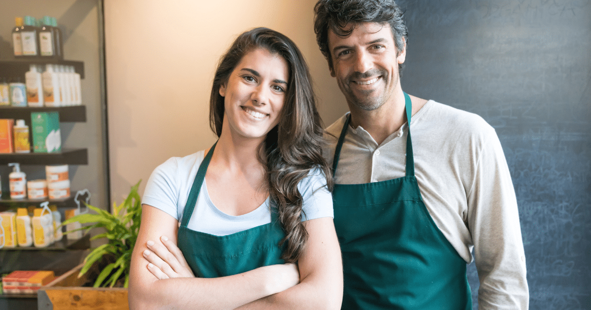 Smiling business owners in aprons, representing small business finance solutions and overcoming money problems.