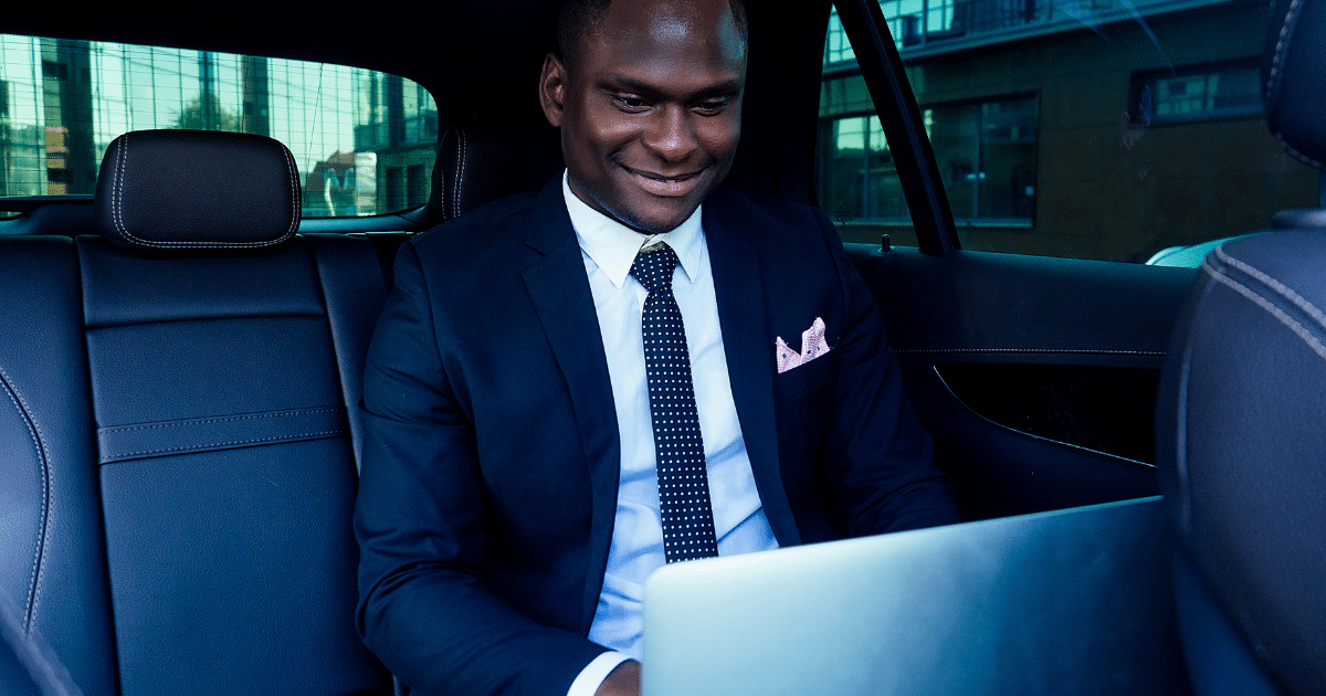 Business professional working on a laptop in a car, highlighting the importance of financial awareness and banking fees.