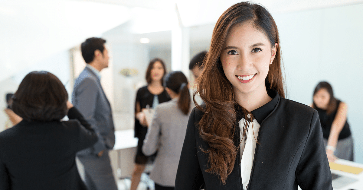 Businesswoman smiling in a professional setting, representing essential apps for small business success and organization.