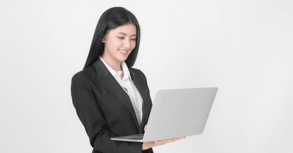 Smiling businesswoman in a suit using a laptop, representing rising confidence among small business owners.