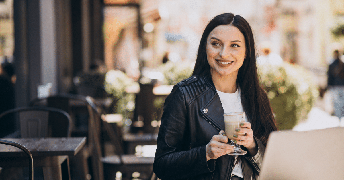 Smiling woman in a cafe holding a drink, representing mobile marketing trends and digital engagement in 2023.