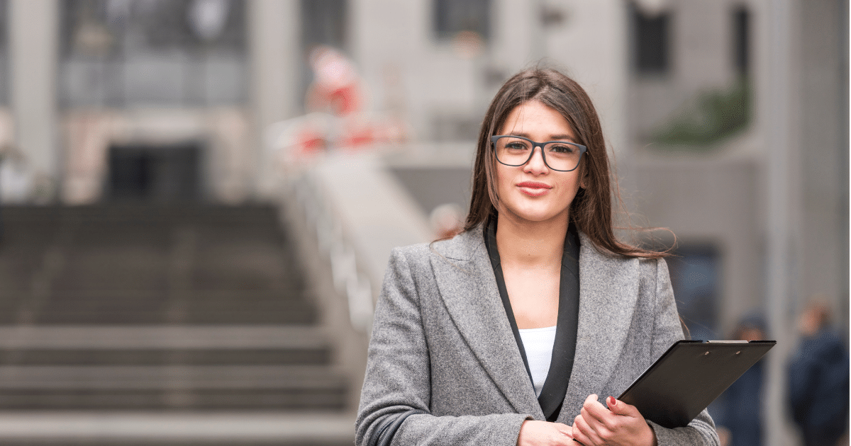 Professional woman holding a clipboard, embodying key traits of a great worker in a dynamic work environment.