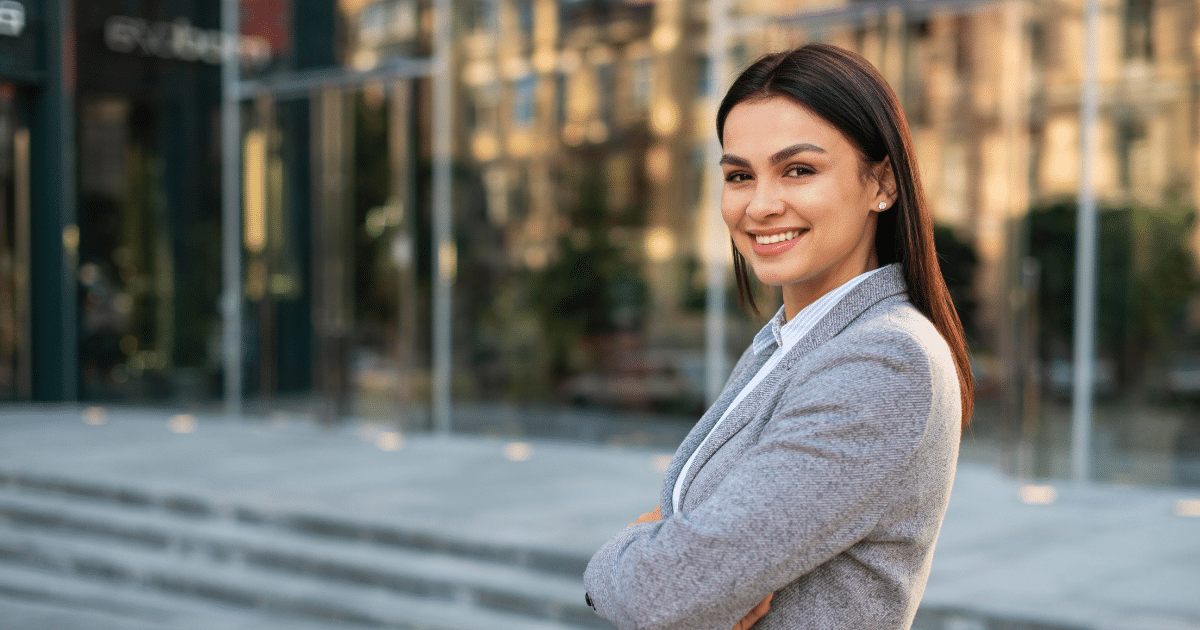 Professional woman smiling confidently outside a modern office, representing effective employee training strategies.