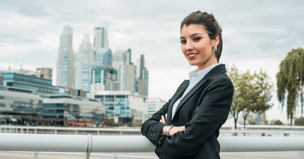 Business professional smiling confidently in front of a city skyline, representing employee pride and motivation strategies.