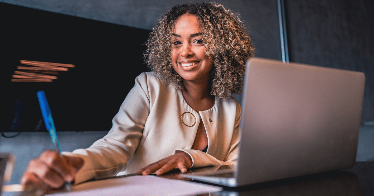 Smiling businesswoman working on a laptop, representing effective expense reduction strategies for small businesses.