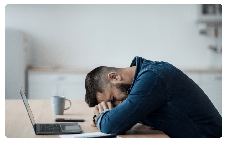 Stressed businessman with head down on desk, highlighting the challenges of the business loan application process.