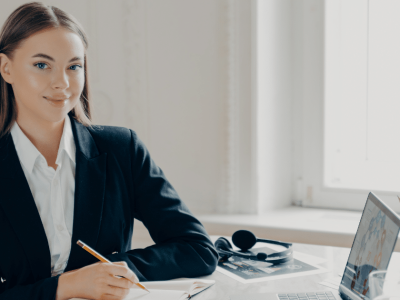 Professional woman at a desk with a laptop, notepad, and headphones, representing effective time management and productivity.