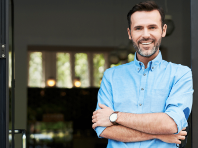 Smiling businessman standing at the entrance, representing business loans and cash advances for entrepreneurs.