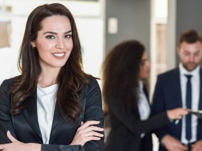 Business professional smiling confidently with colleagues discussing strategies in a modern office setting.