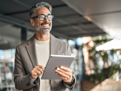 Smiling professional man using a tablet, representing employee empowerment and business growth strategies.