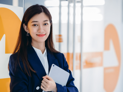 Professional woman in business attire holding a tablet, representing small business owners and the importance of taking vacations.