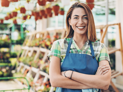 Smiling woman in an apron at a garden center, representing customer service and business growth strategies.