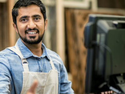 Smiling small business owner at a computer, representing small business financing and growth opportunities.