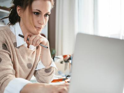 Woman working on a laptop, focused on achieving professional greatness and sustainable success strategies.