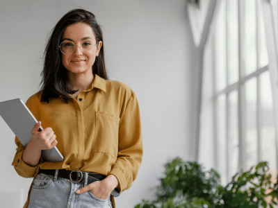 Young businesswoman holding a tablet in a bright office, emphasizing the importance of location in real estate for small businesses.