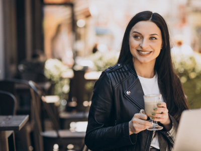 Smiling woman in a cafe holding a drink, representing mobile marketing trends and digital engagement in 2023.