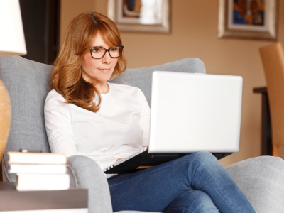 Woman researching fast approval small business loans on a laptop in a cozy living room setting.