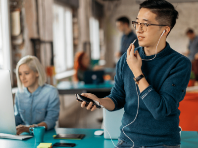 Young professional in a modern office, focused on smartphone, highlighting small business tax tips and financial success.