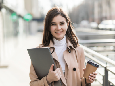 Young professional woman holding a laptop and coffee cup, ready to enhance her workday with office exercises.