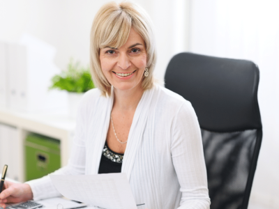 Smiling businesswoman reviewing documents in an office, emphasizing business credit profile scores and funding opportunities.