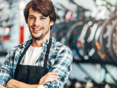 Smiling young man in a bike shop, representing effective marketing strategies for small businesses on a budget.