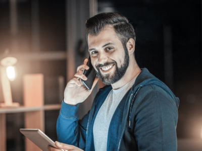 Smiling man on phone with tablet, representing effective credit building strategies without debt.