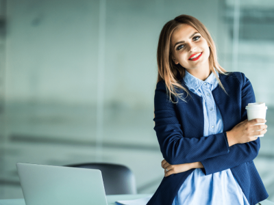 Smiling woman in a business setting holding a coffee cup, representing innovative holiday marketing strategies for restaurants.