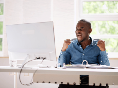 Man celebrating success at a desk, representing family business achievements and effective management strategies.