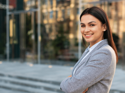 Professional woman smiling confidently outside a modern office, representing effective employee training strategies.