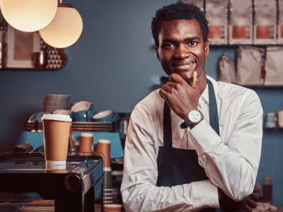 Smiling barista in a coffee shop, representing small business credit building and financing opportunities.