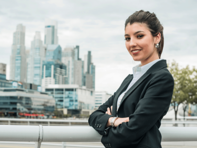 Business professional smiling confidently in front of a city skyline, representing employee pride and motivation strategies.