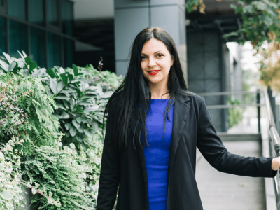 Business professional in a blue dress and black blazer standing outdoors, promoting customer retention strategies for growth.