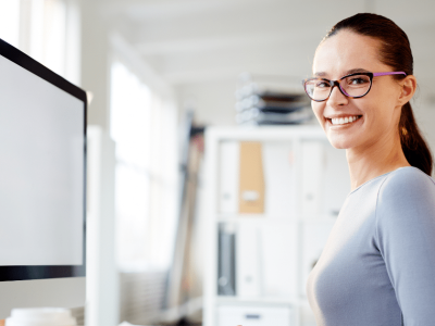 Smiling professional woman in an office, highlighting the importance of a healthy workforce for business success.