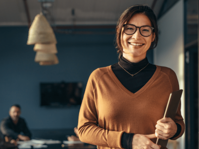 Smiling businesswoman in an office promoting cost-effective social media marketing for small businesses.