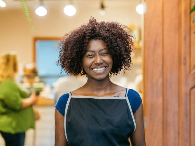 Smiling business owner in an apron, representing loan options for tax payment assistance and financial support.