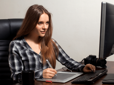 Young woman working on a digital tablet at her desk, focusing on small business growth and planning.