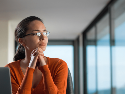 Woman contemplating customer service strategies in a modern office setting, emphasizing over-the-top service excellence.
