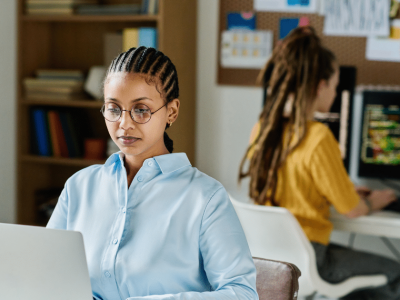 Woman working on a laptop in a modern office, focusing on overcoming public speaking fear and building confidence.