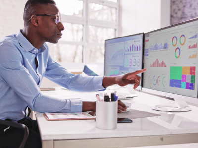 Business professional analyzing financial data on dual monitors, highlighting insights for effective decision-making.