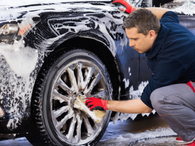Car wash employee cleaning a vehicle, showcasing the importance of funding for business growth and equipment upgrades.